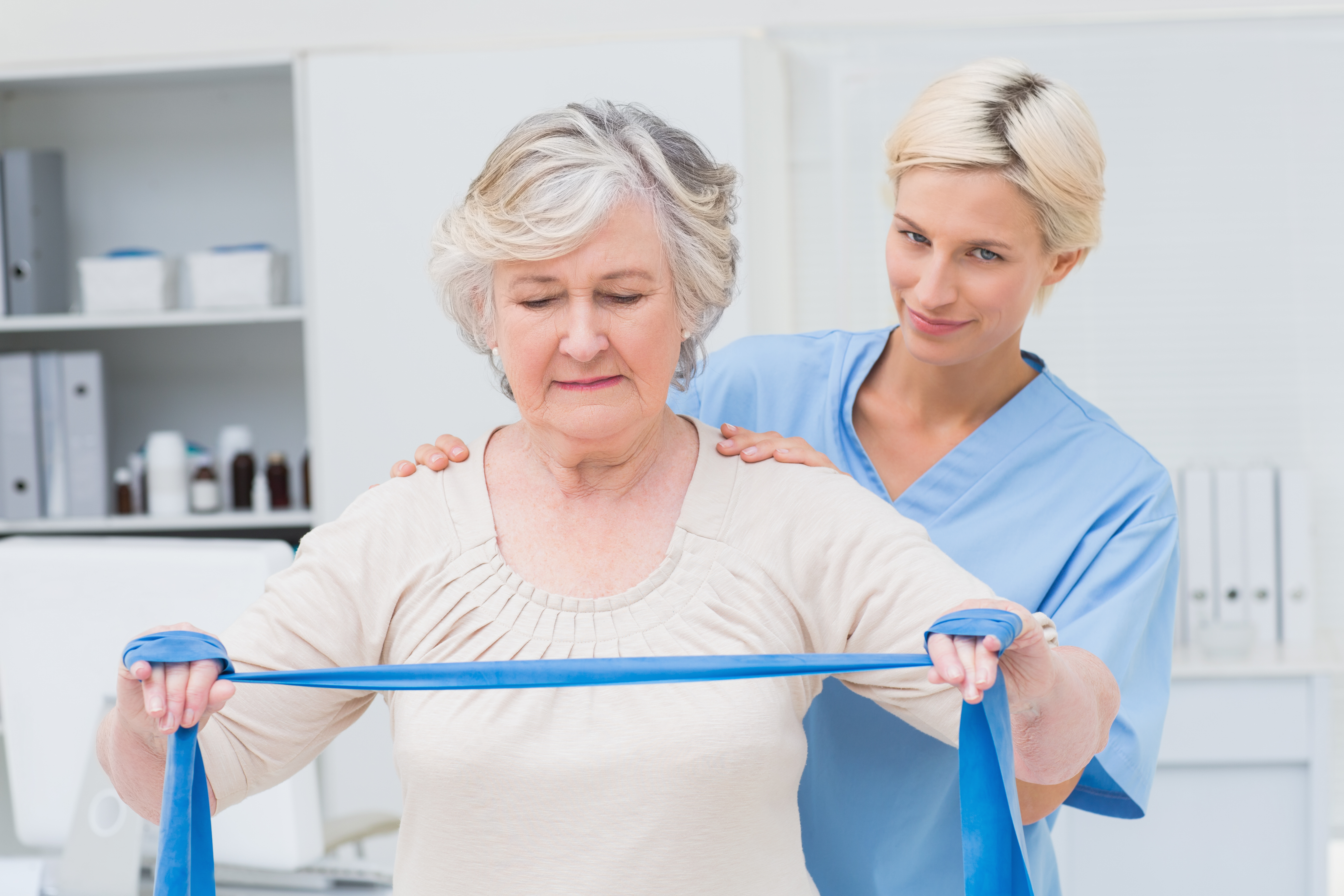 Portrait of confident nurse assisting senior woman in exercising with 